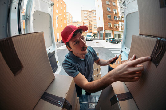 Delivery man checking packages with tablet in van