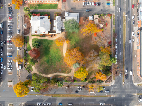 Traffic on busy roads around a city park with colorful Fall tree tops