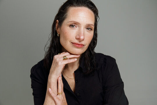 Woman Sitting and Resting Chin on Hand in a Studio Setting