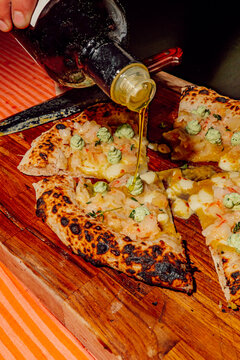 Chef pouring olive oil over fresh artisanal pizza slices