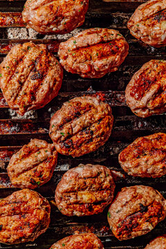 Spiced kofte meat patties cooking on a charcoal grill