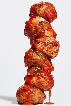 Meatballs in Tomato Sauce Leaning Stack on White Background