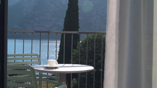 Cup of coffee on a balcony table overlooking the sea on a sunny summer day, peaceful  vacation atmosphere