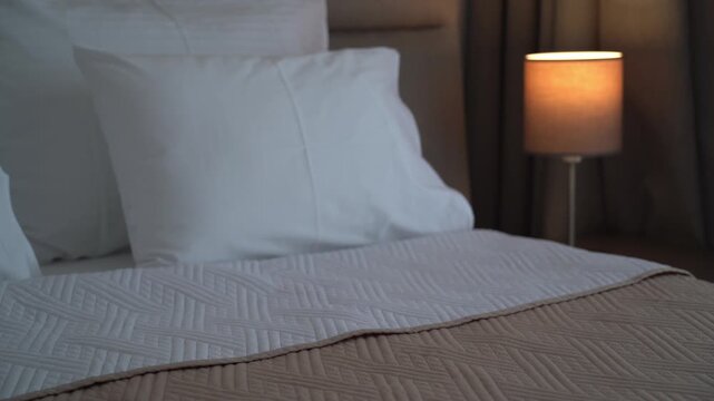 Woman&rsquo;s hands reaching for a book on a bed in a cozy bedroom, quiet reading and relaxation concept