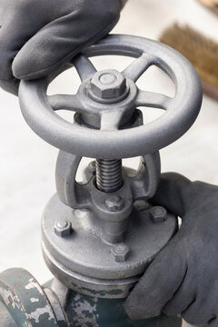 Man wearing protective glove operating industrial steel valve cleaned by sandblasting. Metal surface texture after abrasive treatment. Mechanical equipment maintenance and restoration.