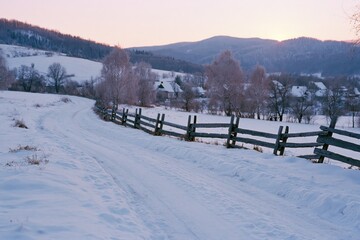 Obraz premium The Snowy Path Through A Quiet Countryside At Sunset With Rolling Hills