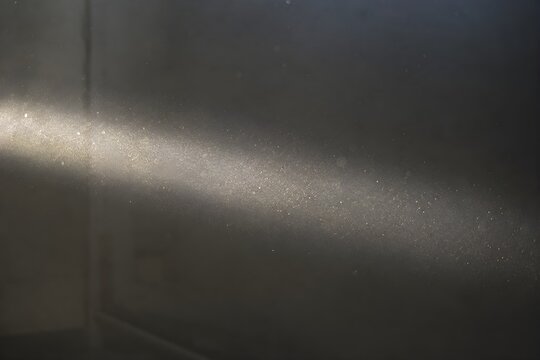 Sunbeam or Light Ray Illuminating Thousands of Floating Dust Particles in a Dark Room