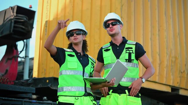 Logistics workers inspecting cargo operations at an industrial freight yard, highlighting shipping, transportation and warehouse management.