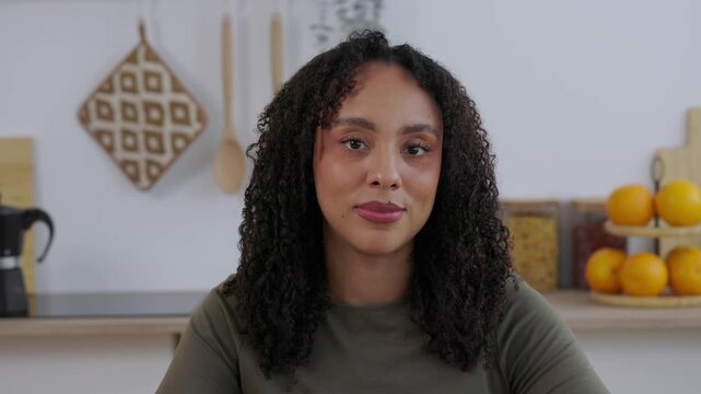 POV of African American businesswoman listening during a video call from home. Young professional attending online business meeting on laptop in a modern kitchen. Remote work and communication concept