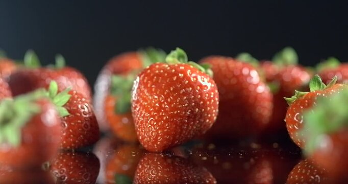 One strawberry rotating around its axis on black background in slow motion