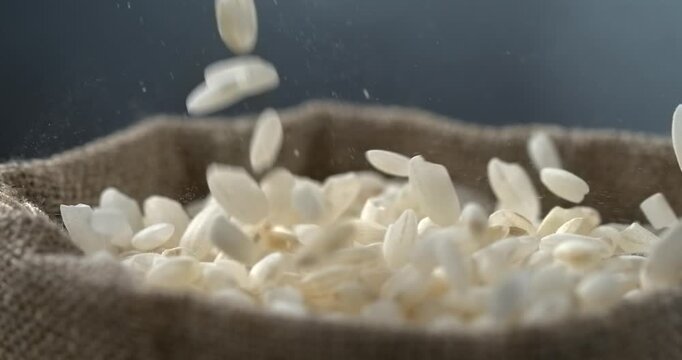 White rice grains falling into burlap sack in super slow motion