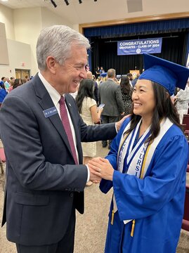 School administrator congratulating nursing graduate in blue gown