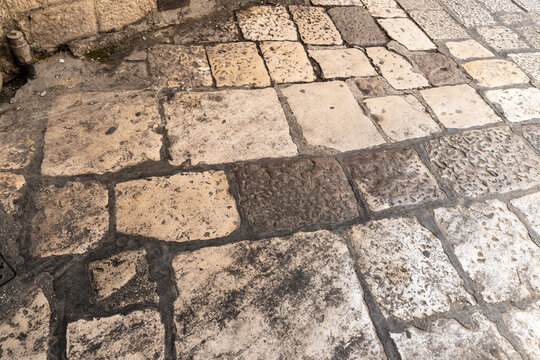 Aerial view of worn cobblestone street pavement with irregular stone blocks and weathered texture