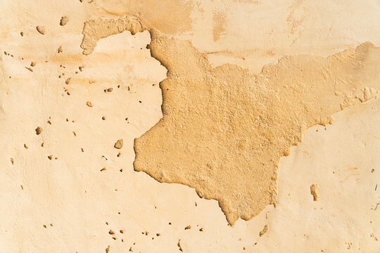 Cracked plaster wall texture with peeling surface revealing layered stone beneath