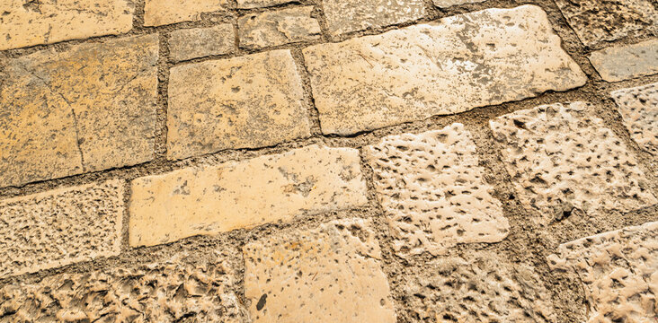 Aerial view of worn stone pavement with rectangular blocks in warm sandy tones