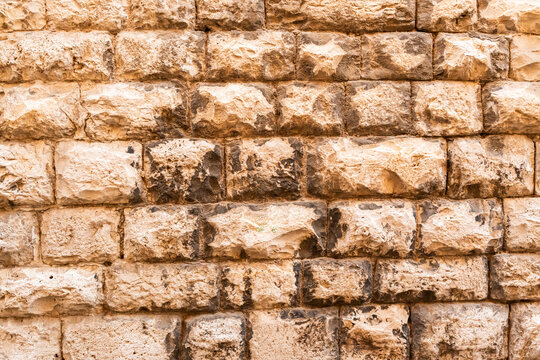 Weathered brick wall texture with warm toned blocks and dark grout in horizontal pattern