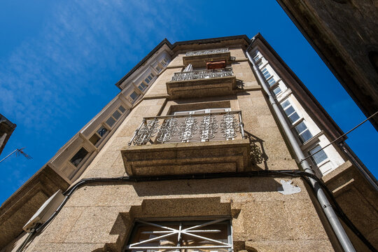 Low angle view of a traditional historic granite building facade with ornate iron balconies and wooden window galerias