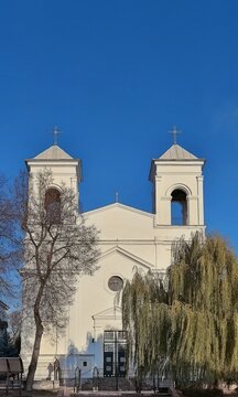 Symmetrical front view of the historic white Catholic Church of the Exaltation of the Holy Cross under a clear blue sky
