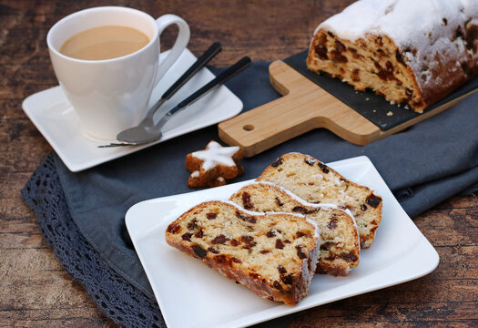Sliced Christmas stollen with a cup of coffee and cinnamon star cookie.