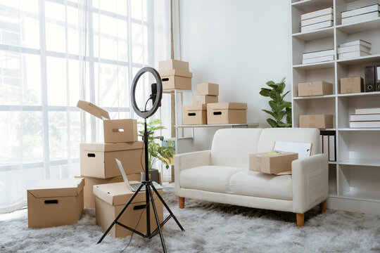 Home-based E-commerce Setup: A bright and organized home office space prepared for online selling, featuring packed cardboard boxes, a ring light on a tripod, a comfortable sofa.