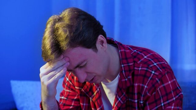 Sick man suffering from a headache and flu symptoms. Concept of a seasonal cold, viral infection, and feeling unwell during a respiratory illness needing home treatment. High quality 4k footage