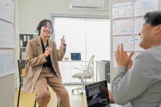 Confident businesswoman pointing at whiteboard chart, explaining strategy and presenting data during office meeting, close-up dynamic angle capturing leadership and business presentation concept