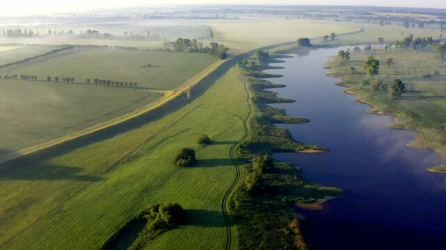 Aerial view of Elbe River winding through green meadows beneath morning fog in Germany, an inspiring scenic destination for travel, tourism and outdoor recreation.