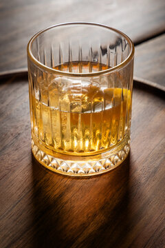 Close up of a classic old fashioned cocktail on a dark wooden background garnished with an orange twist.