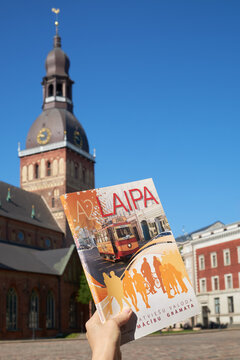 Hand holding A2 level Latvian language textbook on Dome square in Riga Latvia