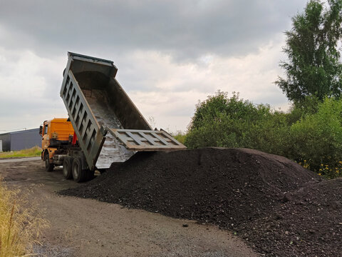 August 1, 2026, Russia: SHACMAN heavy-duty truck unloading soil and gravel at construction site. Heavy machinery dumping rocks for road building project.