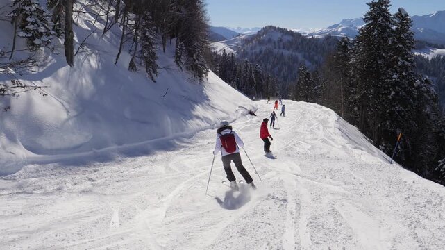 Skiers and snowboarders skiing down prepared ski slope in scenic mountain landscape on sunny winter day. Showcasing winter sports and healthy, active lifestyle in alpine resort