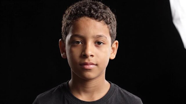 Portrait of a Young Boy with Curly Hair on Black Background