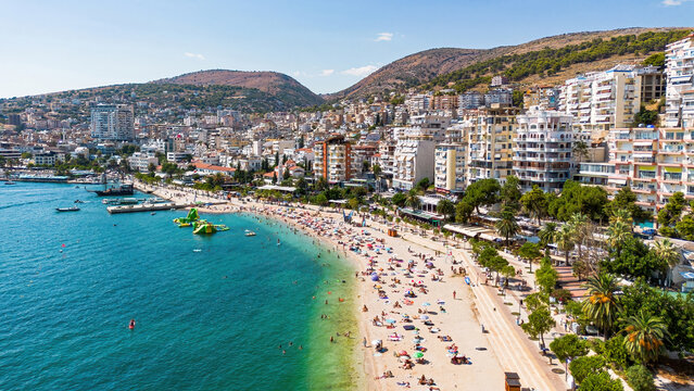 Aerial drone view of the crowded beach, promenade, and coastal buildings of Saranda, Albania