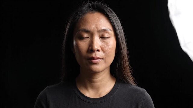 Serious Mature Asian Woman Portrait on Black Background