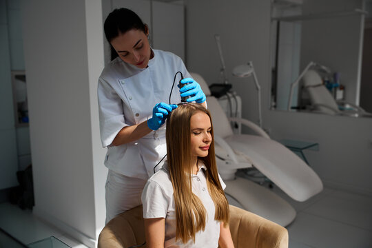 Detailed scalp examination by a dermatologist using a handheld trichoscope device helps identify early signs of alopecia.