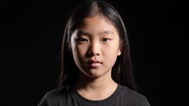 Serious Portrait of a Young Asian Girl on Black Background