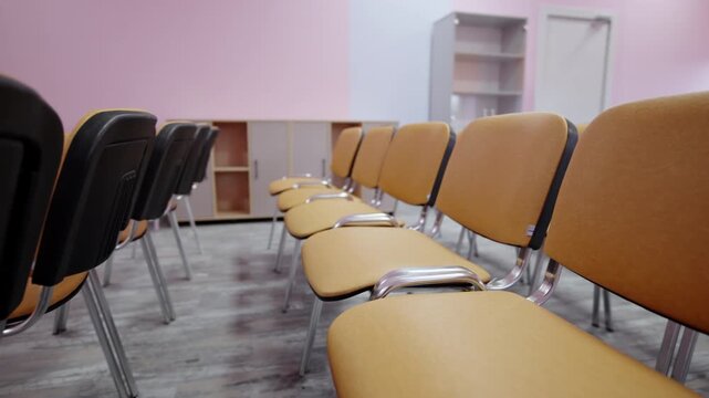 Audience seating extends across clean floor in quiet lecture hall. Orderly furniture arrangement provides comfortable setup for meetings