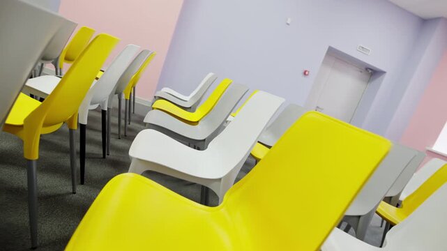 Modern chairs stand neatly aligned on carpet floor in lecture room. Bright color contrast creates cheerful and professional seminar space