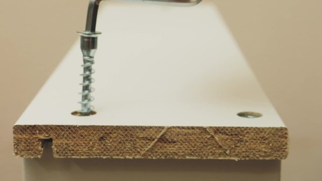 Human hands use a screwdriver to screw screws into furniture with drawers. The middle plan.