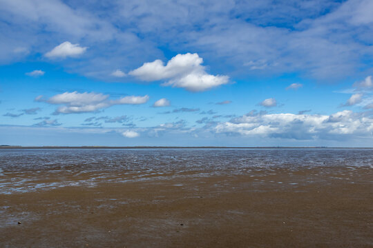 Wadden sea mudflats at low tide with blue sky
