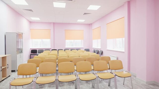 Multiple rows of chairs fill auditorium under bright panel lights. Ventilation setup ensures fresh air and comfortable event atmosphere