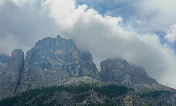 serene rocky mountain peaks covered by clouds in a mystical and serene mountainous landscape viewed from a low angle, looking up at the towering trees and rugged terrain.