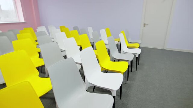 Audience seating features combination of vibrant colorful chairs. Spacious interior creates energetic atmosphere for corporate sessions