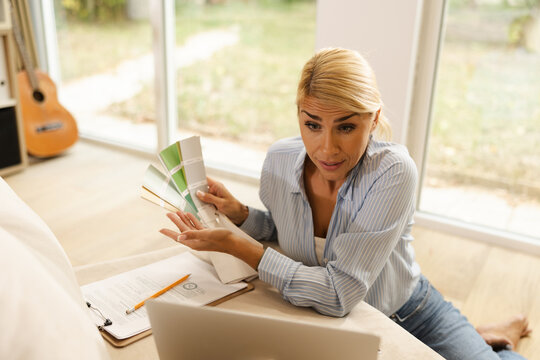 Woman Discussing Plans in a Small Office While Reviewing Materials on Her Laptop