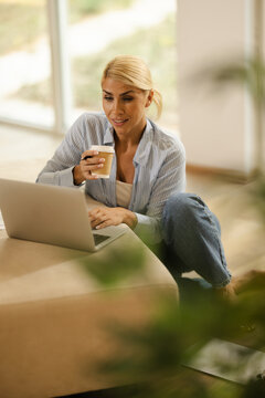 Woman Working in a Small Office at Home While Drinking Coffee and Using a Laptop During the Day