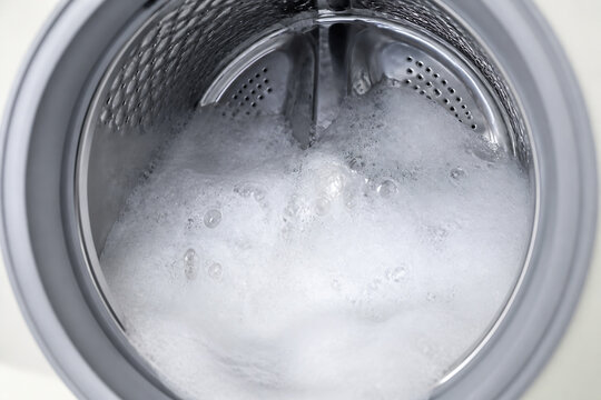 A close-up view inside a washing machine drum filled with suds and water.