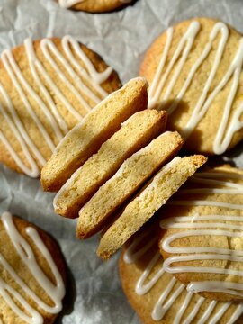 Glazed lemon cookies with cut halves stacked on parchment paper top view