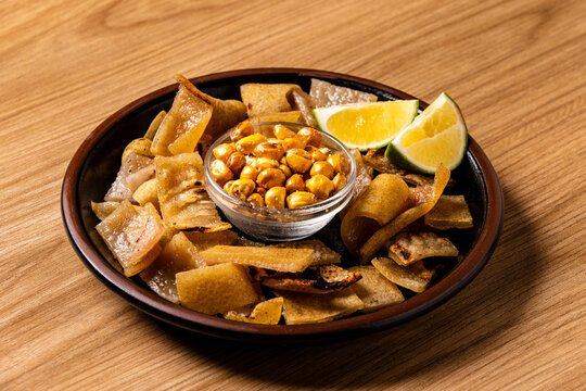 Traditional Crispy Pork Rinds Chicharron Served with Toasted Corn called "Tostado" and Fresh Lemon slices