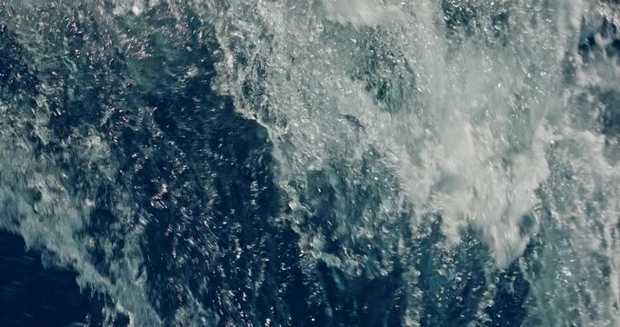 water splashes from under a moving catamaran at sunny day, crystal clear azure water, sea foam, blue color, waves