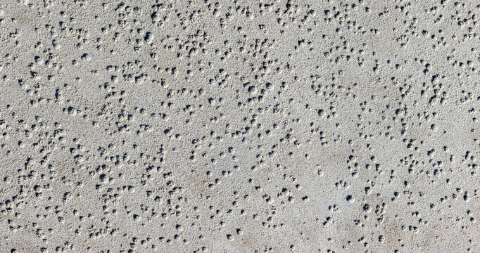 Sandtextur Nahaufnahme mit kleinen Blasenhuegeln und dunklen Mineralkoernern als Hintergrundstruktur